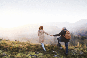 Two senior friends smiling at each other while walking outdoors, sharing a joyful moment.