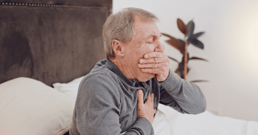 Senior sitting comfortably practicing 4-7-8 breathing with eyes closed, in a bright living room