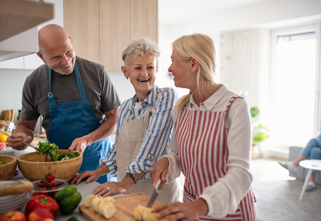 A group of seniors participating in a calm social activity such as cooking, gardening, or volunteering. Natural smiles, positive energy.