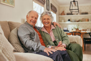 A smiling senior couple sitting closely together on a sofa showing trust and emotional safety.