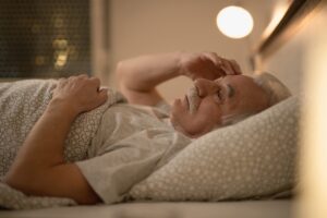 A senior man or woman resting peacefully in a softly lit bedroom, preparing for sleep without screens